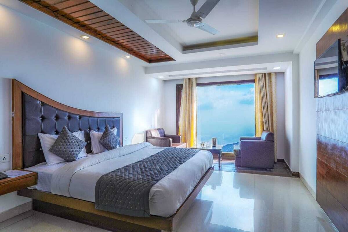 A modern hotel room with a large bed, a ceiling fan, and a view of the ocean.