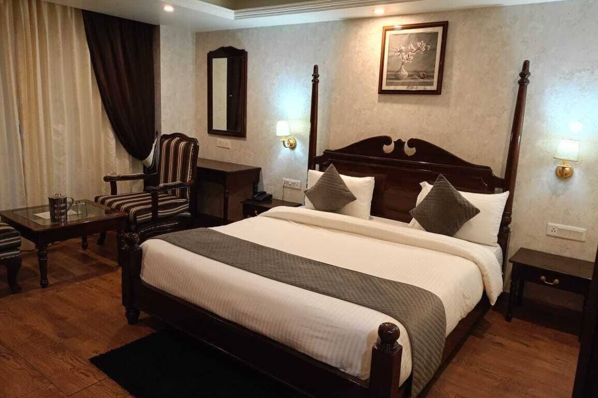 A neatly arranged hotel room with a large bed, a chair, a table, and a nightstand.
