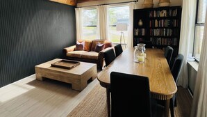En moderne stue med et træspisebord, sorte stole, en sofa og en reol.