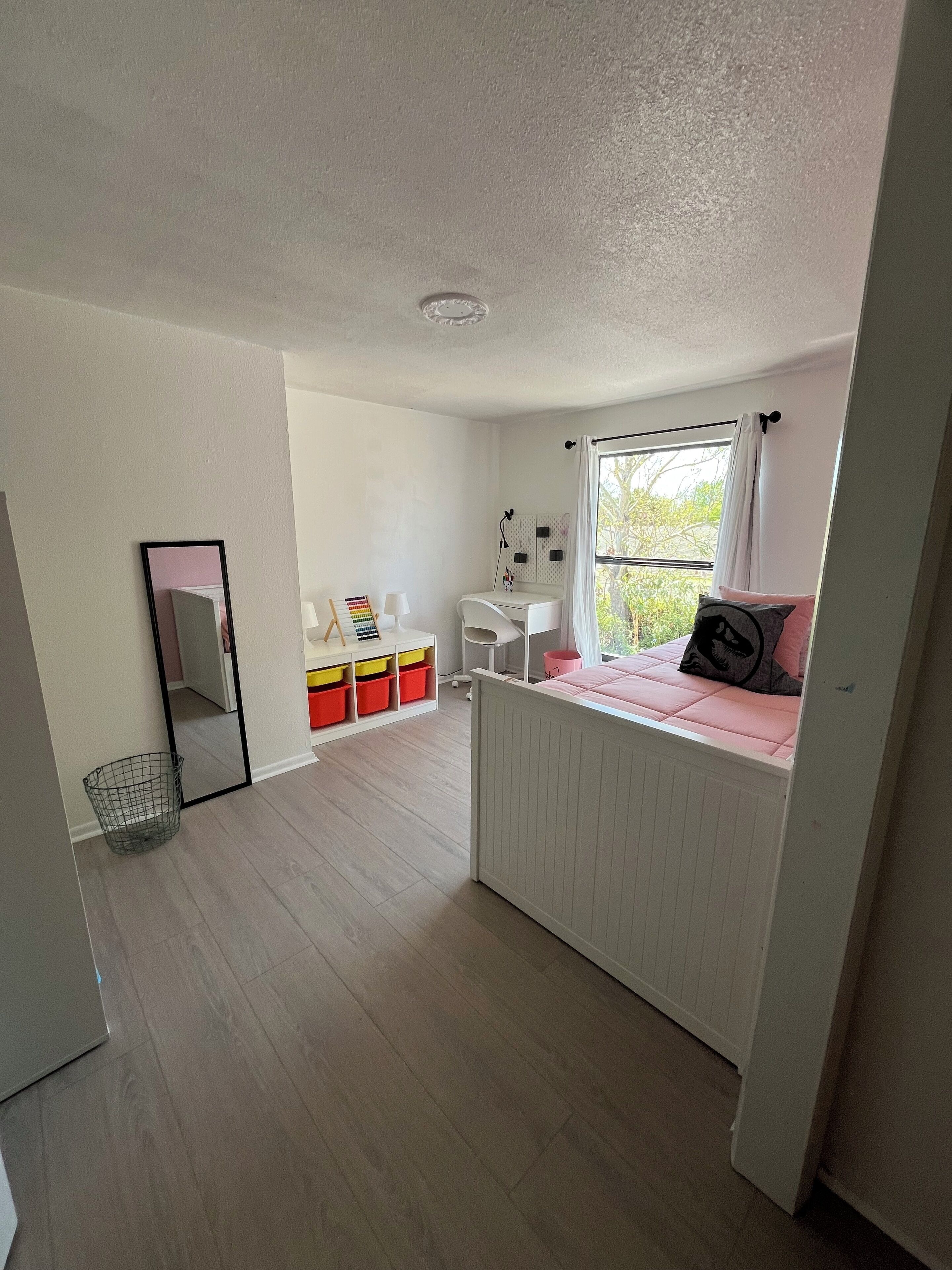 A bedroom with a bed, a desk, a chair, and storage units.