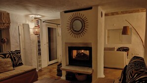 Una sala de estar acogedora con chimenea, un sofá, una mesa de madera y una estantería.