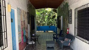 Une terrasse couverte avec un sol en pierre, des sièges d’extérieur et une fresque murale.