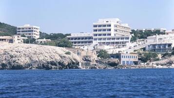 A coastal building complex with multiple floors, situated near a rocky shoreline.