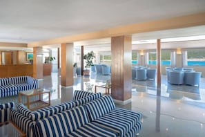 Un hall d’entrée spacieux avec un comptoir de réception, des coins salon et une vue sur la mer.