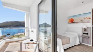 Un balcon avec vue sur la mer et un lit agrémenté d’un tableau.
