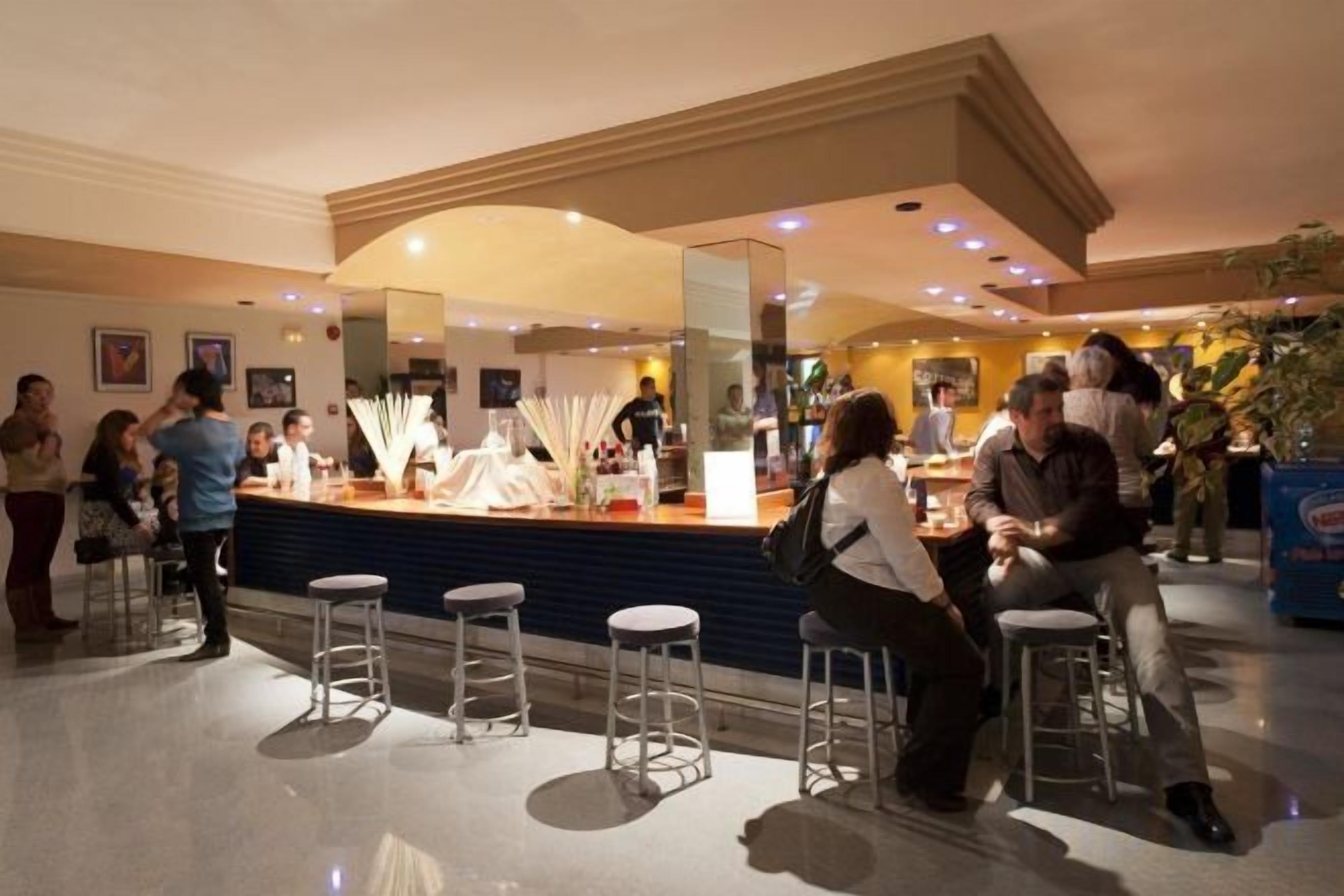 Un hall de hotel con mostrador de recepción, zona de bar y asientos.