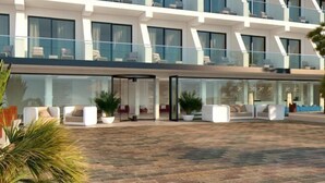 Ein modernes Hotel mit großzügiger Außenbestuhlung, großen Fenstern und einem klaren, zeitgemäßen Design.