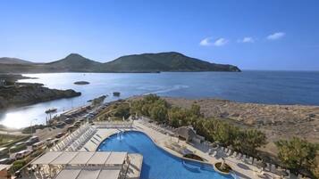 A resort pool with a view of the sea and mountains.