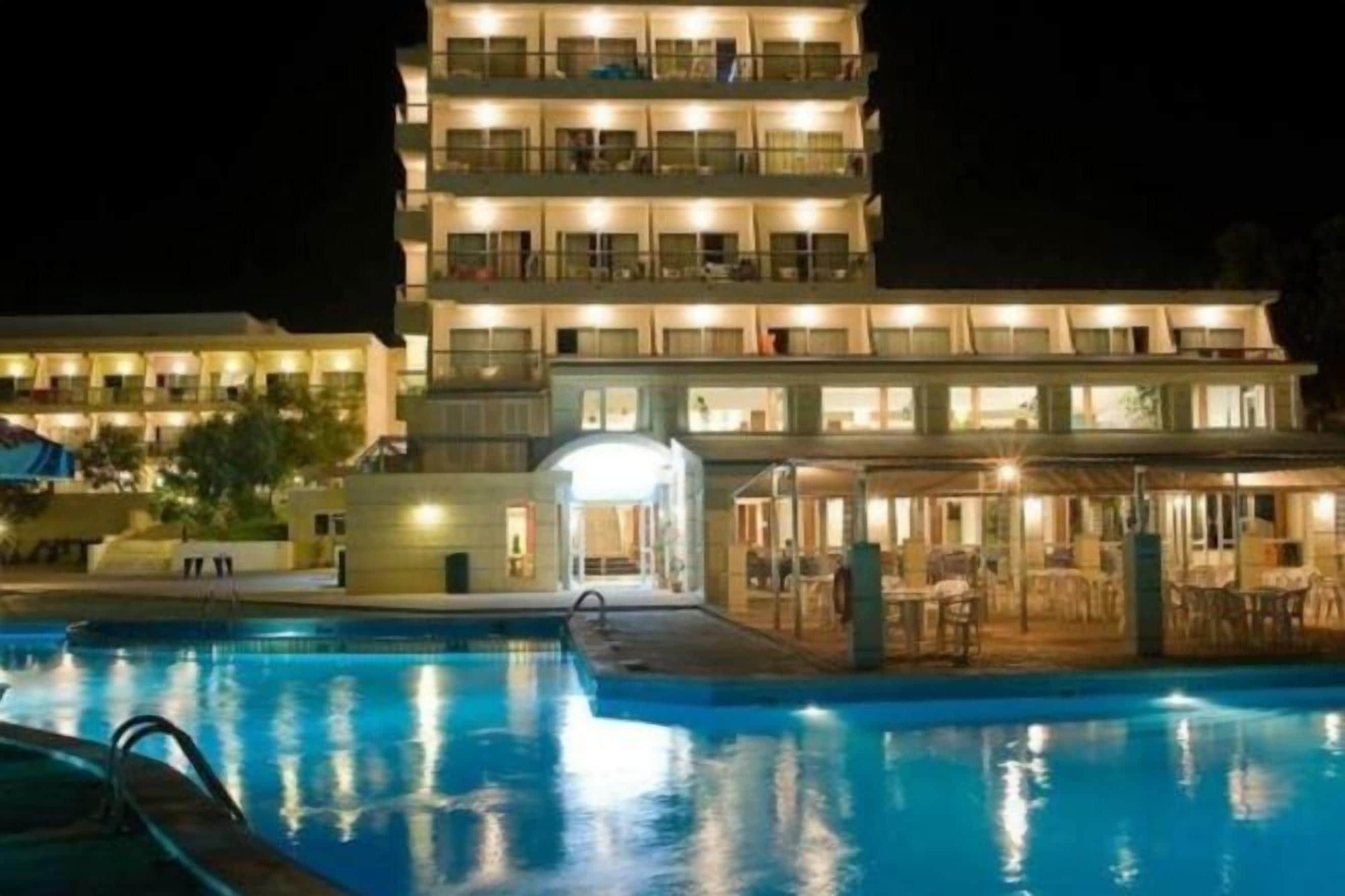 Ein mehrstöckiges Hotel mit Schwimmbecken im Vordergrund.