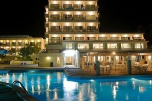 Un hotel de varios pisos con una piscina al frente.