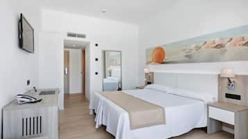 A hotel room with a bed, bedside tables, a desk, and a painting on the wall.