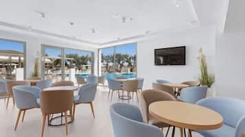 A modern hotel lobby with a pool view, seating arrangements, and a flat-screen TV.