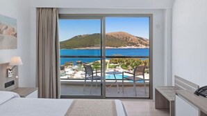 Ein Hotelzimmer mit einer großen Glasschiebetür, die auf einen Balkon mit Pool und Sitzgelegenheit führt.