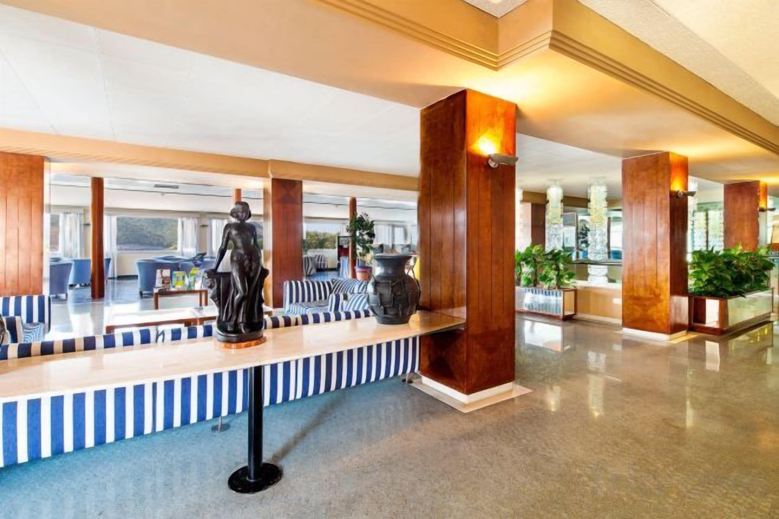 Eine Hotelhalle mit Empfangstresen, Sitzgelegenheiten und großen Holzsäulen.