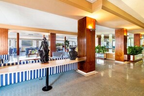 Un vestíbulo de hotel con mostrador de recepción, zona de estar y grandes pilares de madera.