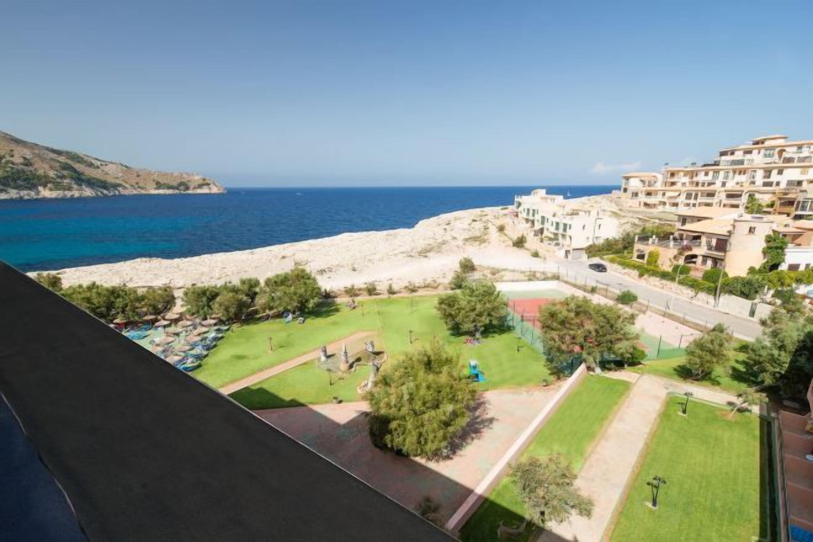 Vista costera con playa, parque verde y un conjunto de edificios.