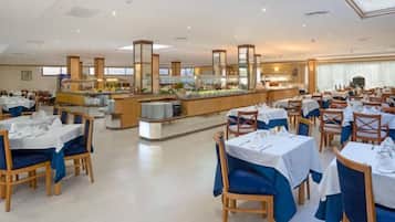 A spacious dining area with multiple tables and chairs, a central buffet, and a bright, well-lit environment.