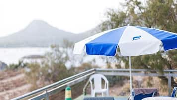 A beachside view with a blue and white umbrella, a chair, and a table.