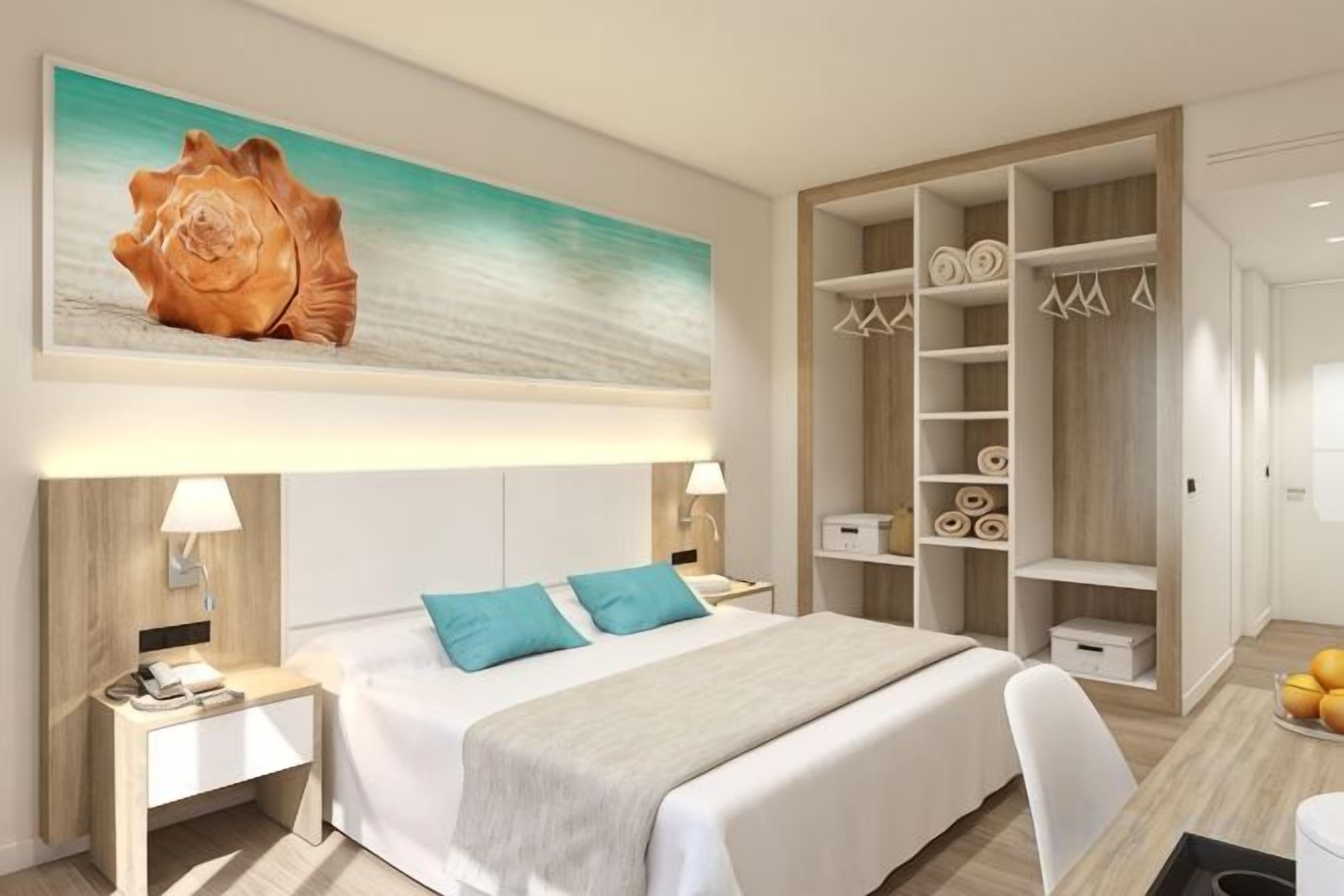 Habitación de hotel con una cama, mesitas de noche, una obra de arte grande, un armario y una estantería con objetos decorativos.