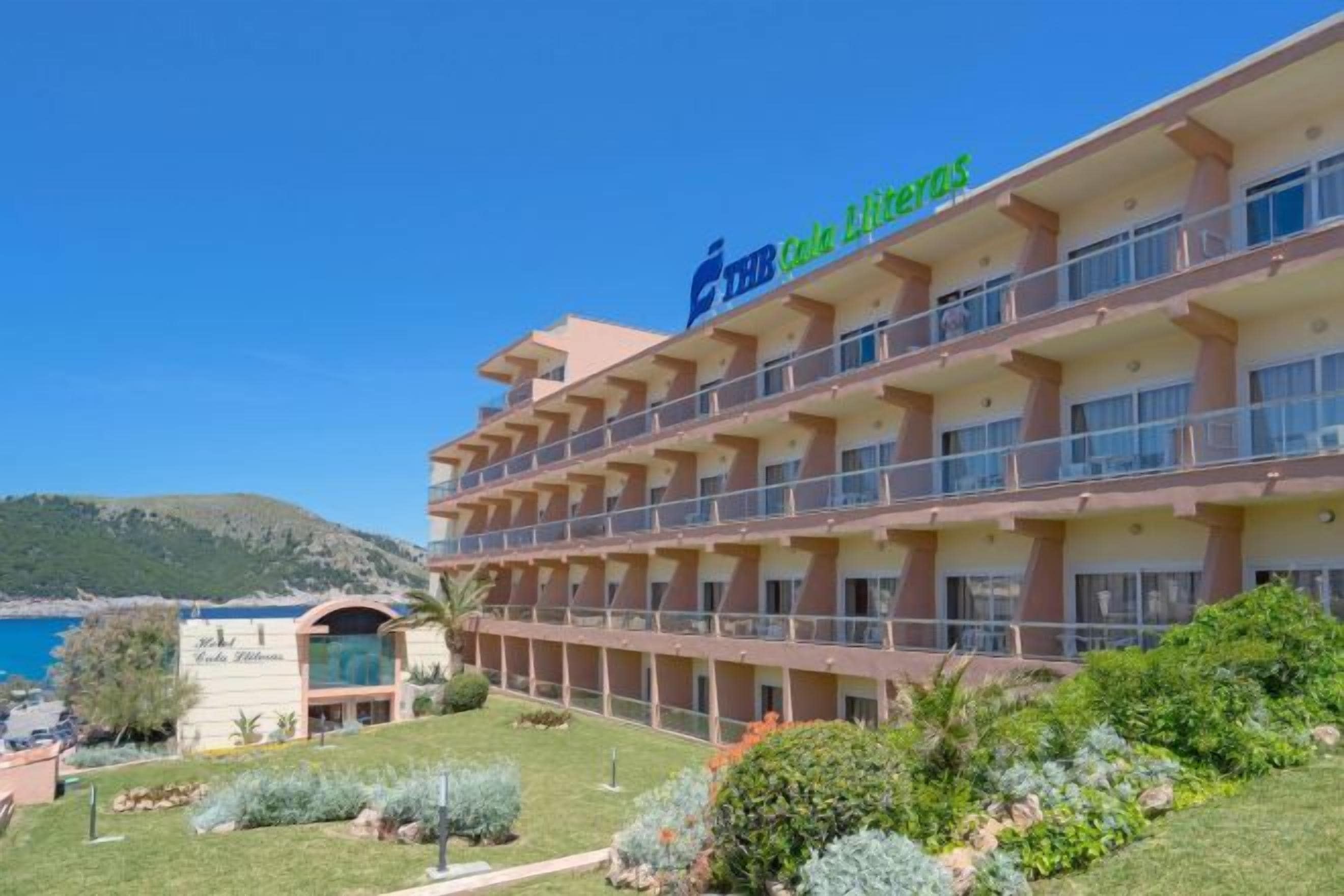 A multi-story hotel with balconies, a pool area, and a view of the sea.