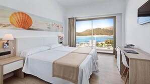 Ein Hotelzimmer mit Bett, Schreibtisch und großem Fenster mit Blick auf das Meer und die Hügel.