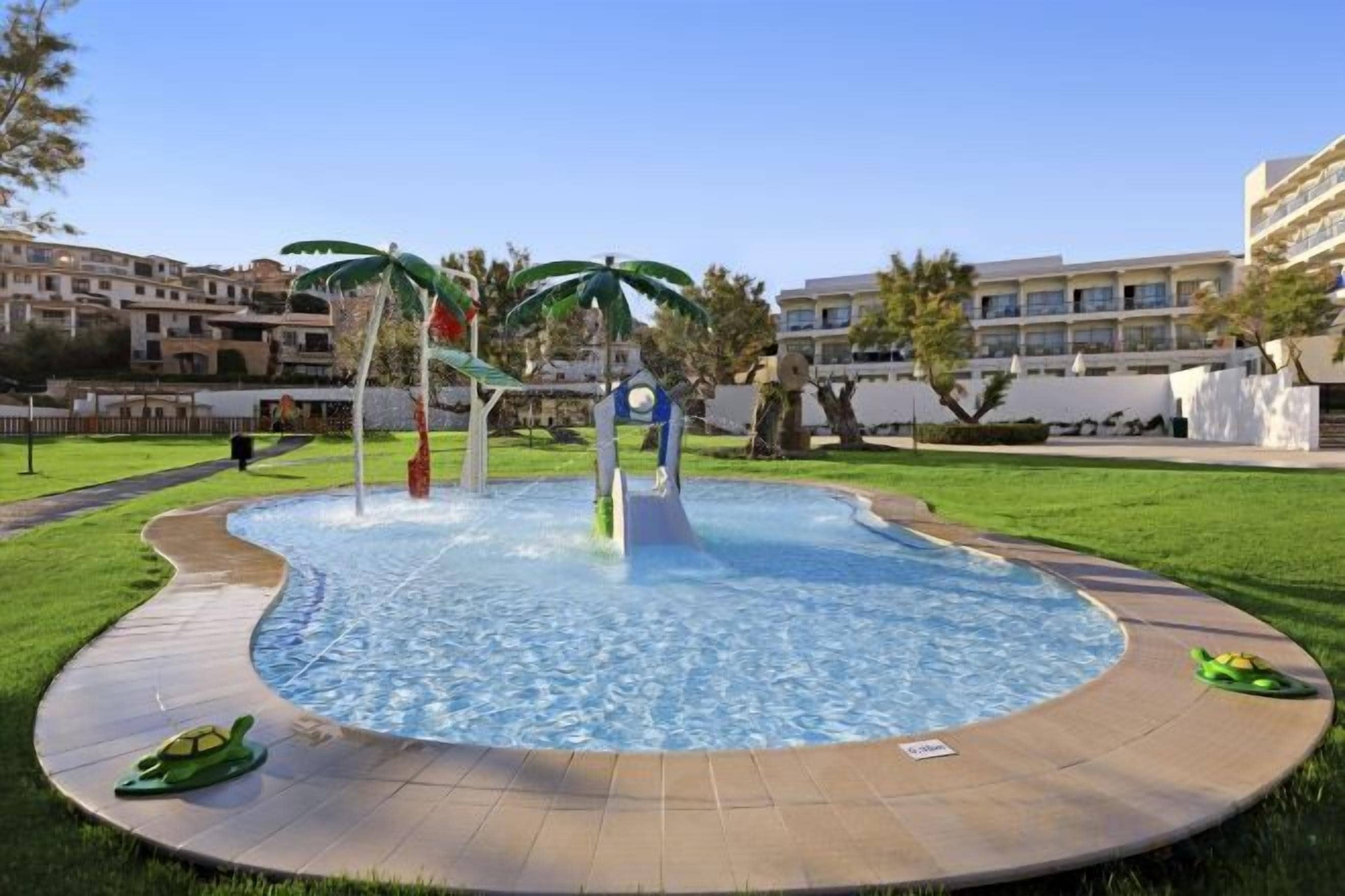Una piscina con diseño circular, rodeada de un área pavimentada y palmeras.