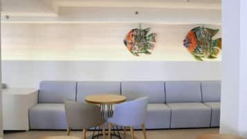 Un intérieur moderne avec un canapé, une table ronde et des chaises, ainsi que deux œuvres d’art représentant des poissons, accrochées au mur.