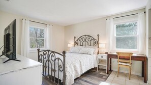Une chambre à coucher comprenant un lit, des tables de chevet, un bureau et une chaise.