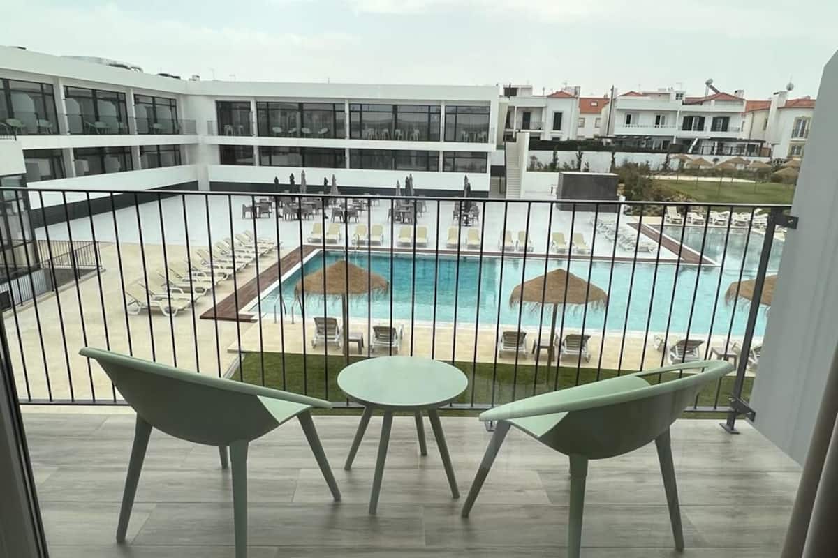 Un balcon avec vue sur une piscine et une plage.