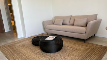 A living room with a beige sofa, two black round coffee tables, and a woven rug.