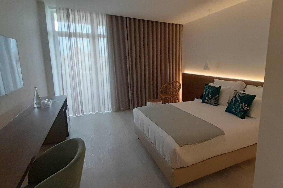 Une chambre d’hôtel moderne, dotée d’un grand lit, d’un bureau et d’une chaise.