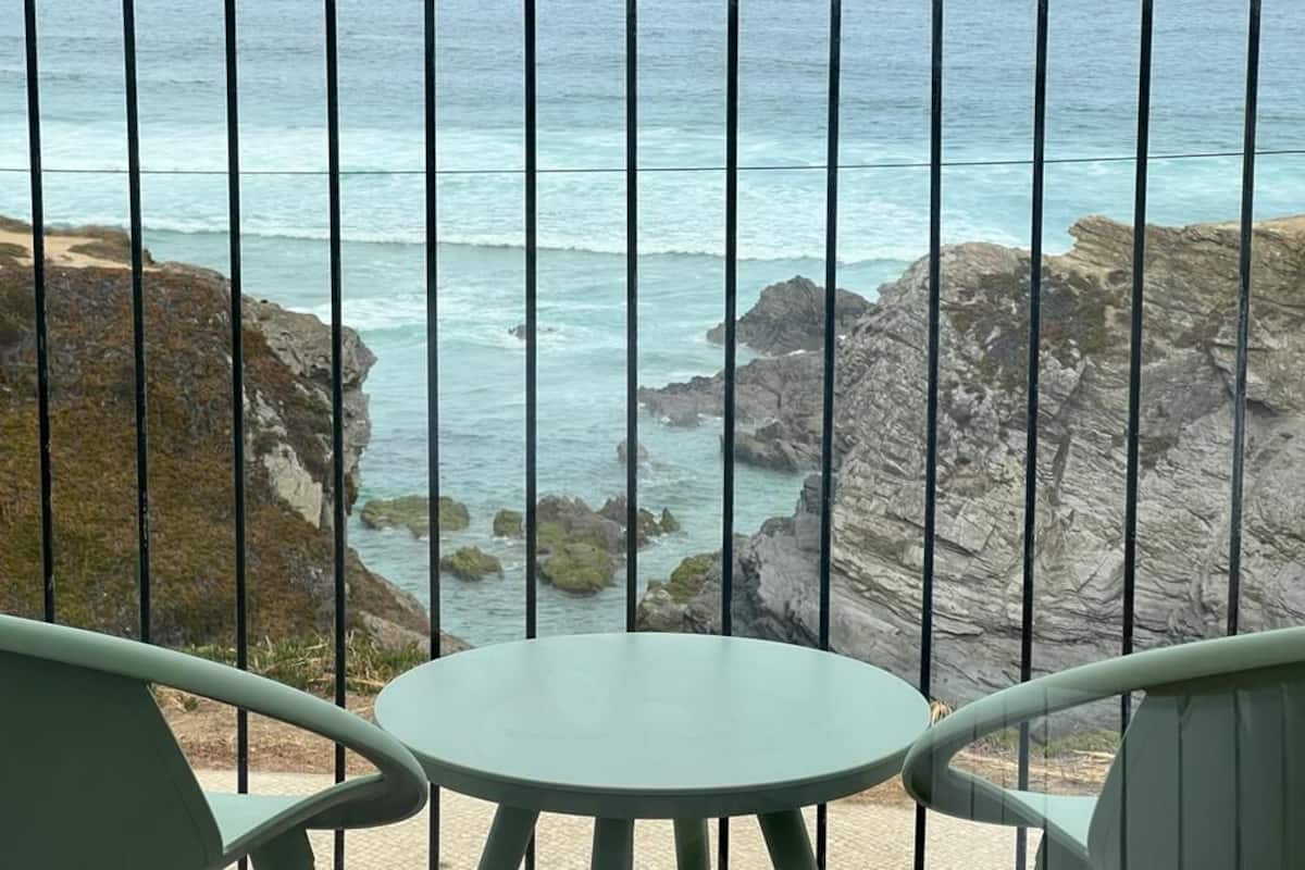 Un balcon avec vue sur l’océan et les falaises rocheuses.