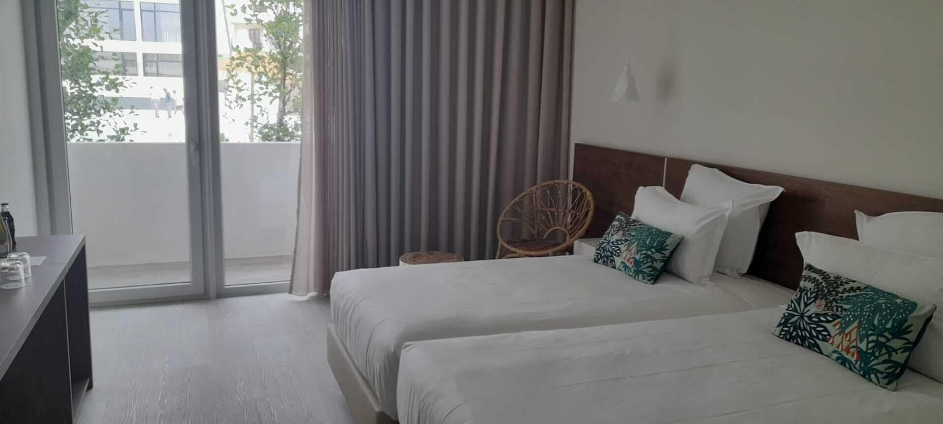 A hotel room with two beds, a desk, and a chair.