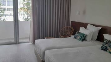 A hotel room with two beds, a desk, and a chair.