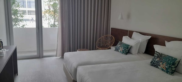 A hotel room with two beds, a desk, and a chair. - Porto Covo Praia Hotel & SPA (Sines)