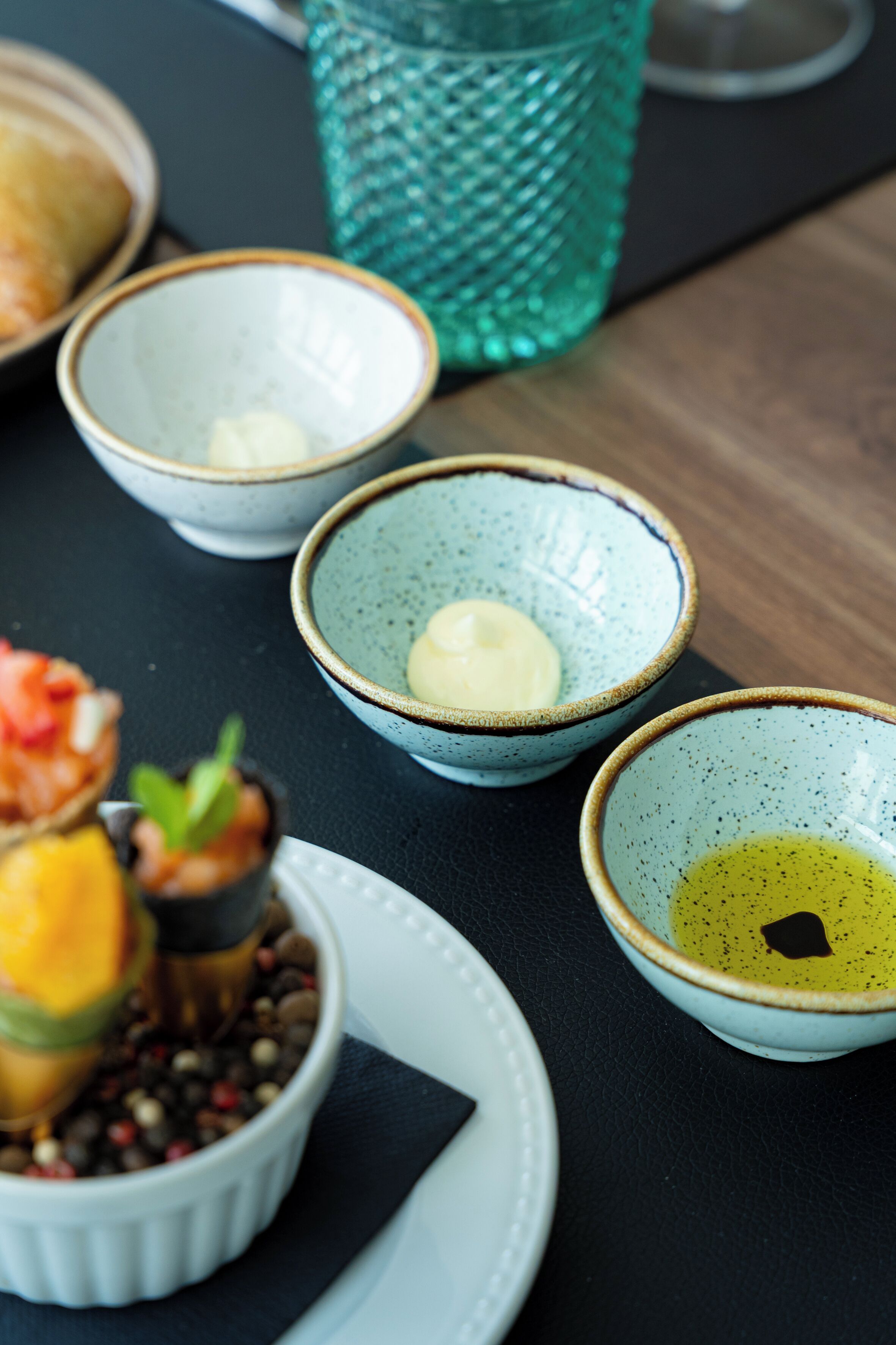 Uma mesa com diferentes recipientes com alimentos, um copo e um prato.