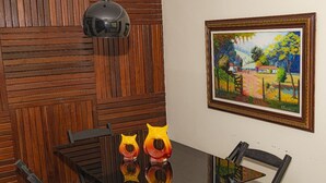 A dining area with a wooden wall, a framed painting, and a table with chairs. - MANSION SALE NEW (Europa Belo Horizonte)
