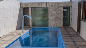 An outdoor swimming pool with a blue border, a water fountain, and a stone wall backdrop. - MANSION SALE NEW (Europa Belo Horizonte)