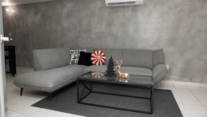 A modern living room with a grey sofa, a glass coffee table, and holiday decorations.