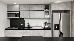 A modern kitchen with a stainless steel refrigerator, microwave, and gas stove.