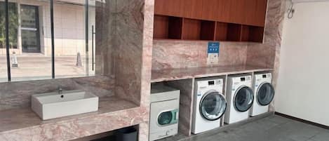 A laundry area with a sink, washing machines, and wooden cabinets.