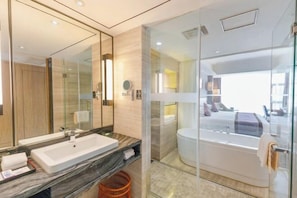 A modern bathroom with a large mirror, a sink, and a glass-enclosed shower area.
