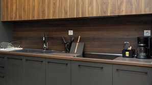 Eine moderne Küche mit Holzschränken, einer Edelstahlspüle und einer Kaffeemaschine.