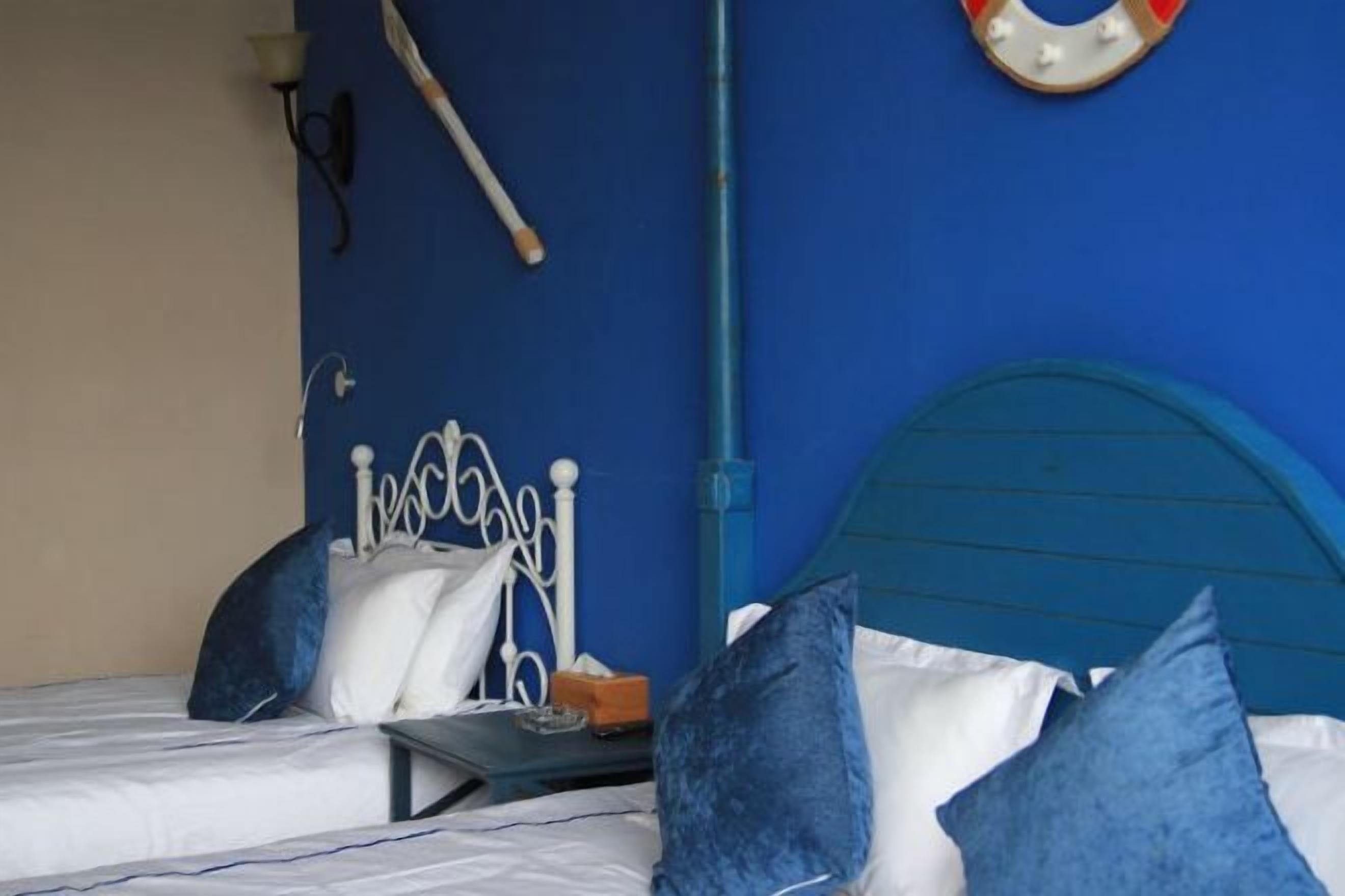 Un letto con struttura in metallo e testata blu, lenzuola bianche e cuscini azzurri.