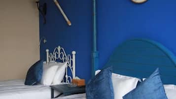 Un letto con struttura in metallo e testata blu, lenzuola bianche e cuscini azzurri.
