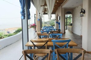 A restaurant with outdoor seating, wooden tables, and blue chairs. - Shengsi Blue Castle Scenic Apartment (Liujingtan) (Shengsi)