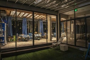 A room with a glass wall, a dining area with tables and chairs, and a small seating area with a chair and a table. - Shengsi Blue Castle Scenic Apartment (Liujingtan) (Shengsi)