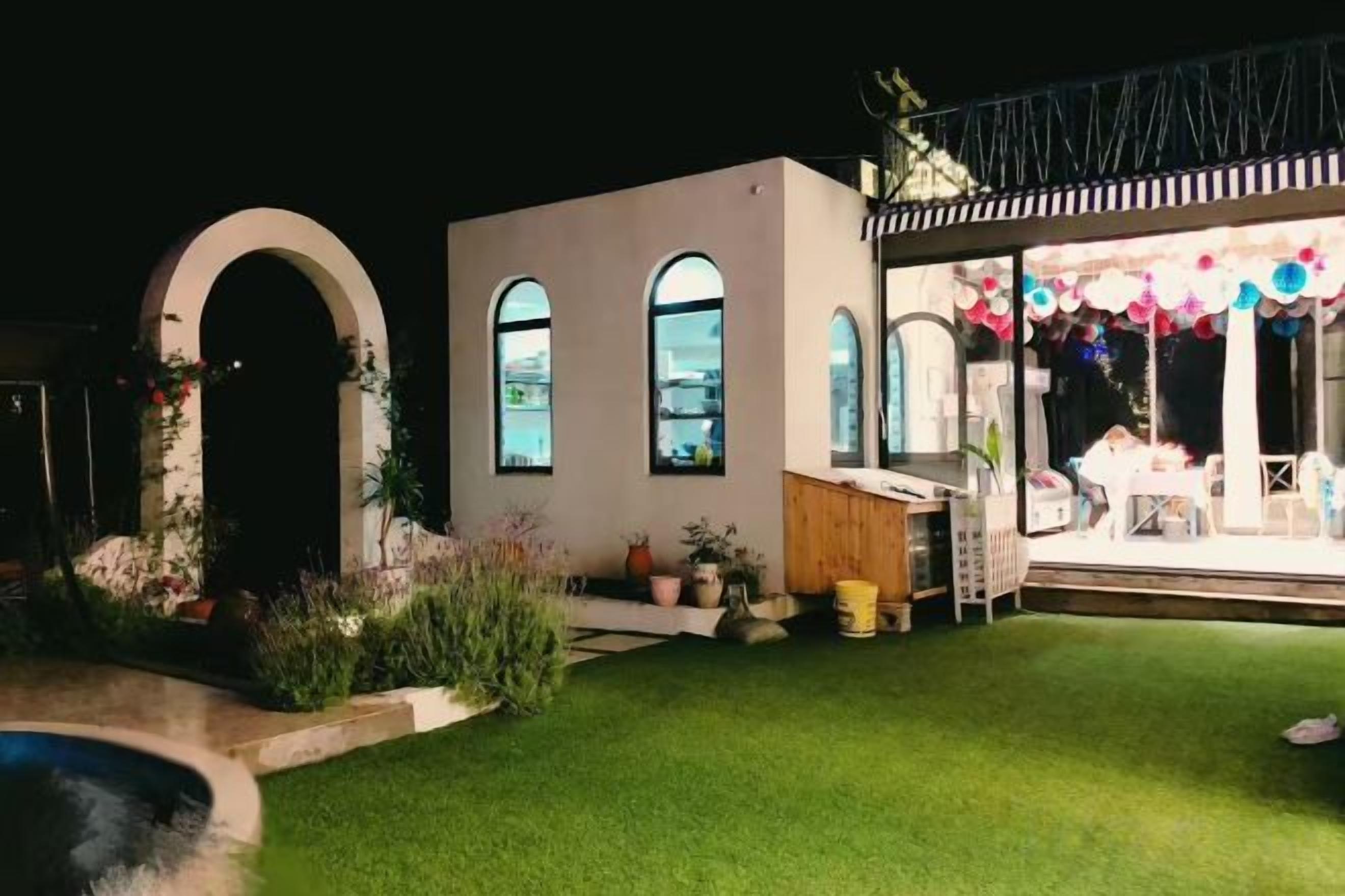 A house with a well-maintained lawn, a patio area with a table and chairs, and a covered outdoor space with a view of the city.