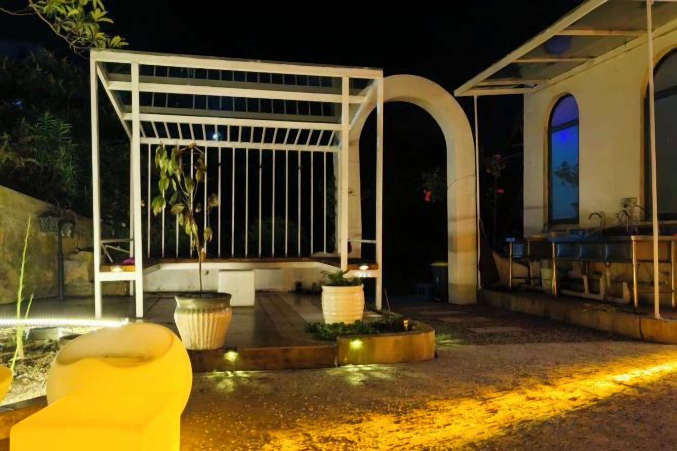 An outdoor patio area with a pergola, seating, and planters.
