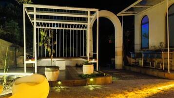 An outdoor patio area with a pergola, seating, and planters.
